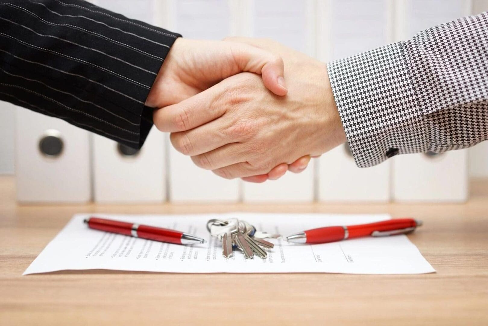 Two people shaking hands over a contract